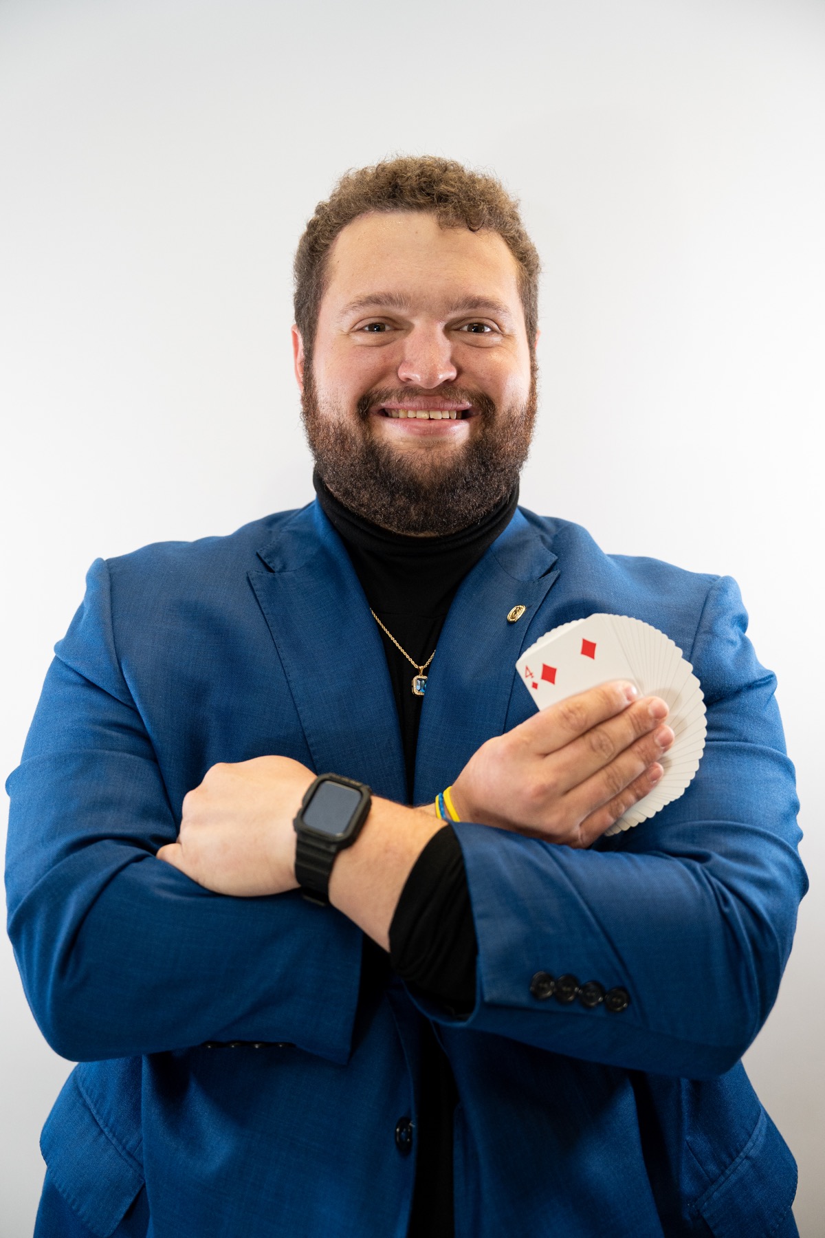 Bryce in a blue jacket holding a fan of playing cards